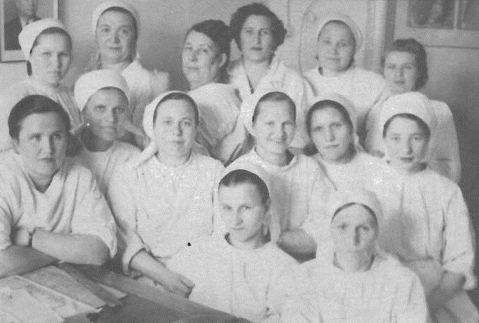 Вагина Устинья Алексеевна. Медсестра больницы им. Сталина г. Осинники. Сверху 3-я слева (в полоборота)